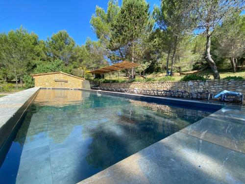 - une piscine avec un mur en pierre et des arbres dans l'établissement LE MAS 5 étoiles SPA Saint Quenin-26 personnes- Accueil Familles et événements MONT VENTOUX PROVENCE, à Saint-Romain-en-Viennois