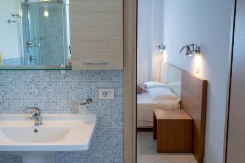 a bathroom with a sink and a bedroom at Sikelika Residence Sul Mare in Scoglitti