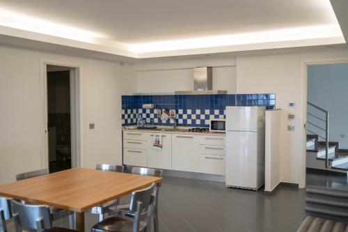 a kitchen with a wooden table and a refrigerator at Sikelika Residence Sul Mare in Scoglitti