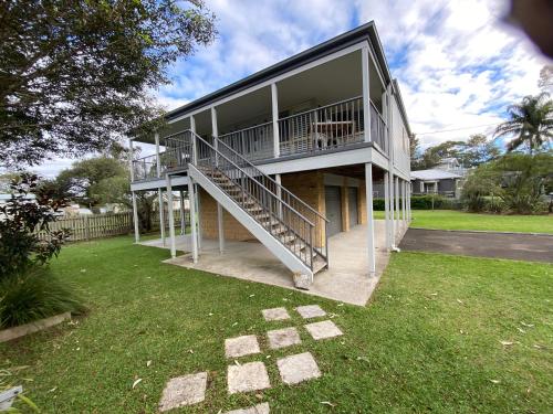 a large house with a staircase in the yard at Bungalow by the River in Shoalhaven Heads