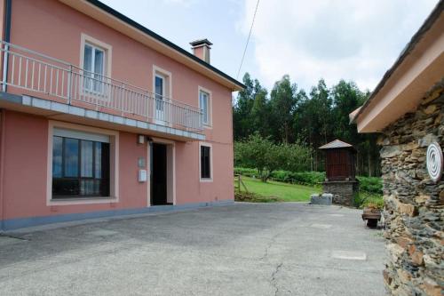 un edificio de color rosa con un balcón en el lateral. en Villa Montedonigo, en Loiba