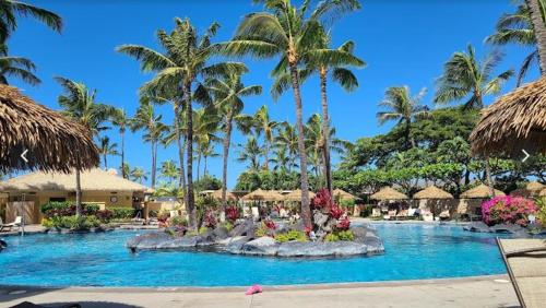 a pool at a resort with palm trees and umbrellas at Marriott Ko olina beach club in Honokai Hale