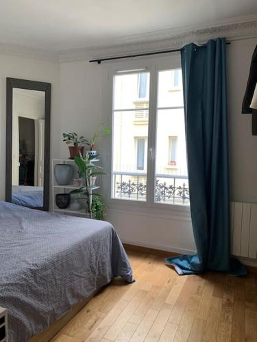 une chambre avec un lit et une grande fenêtre dans l'établissement Appartement de charme à proximité des puces, à Saint-Ouen