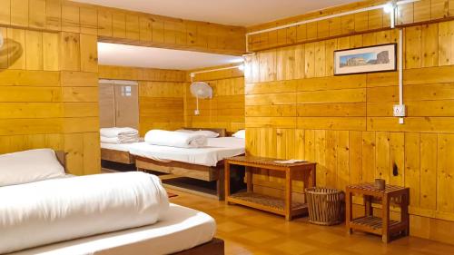 2 camas en una habitación con paredes de madera en SDD Bamboo Village Resort en Uttar Simlabari