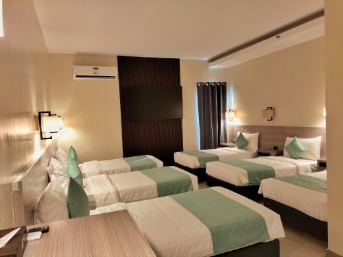 ein Hotelzimmer mit 3 Betten und einem Tisch in der Unterkunft WATERWORLD HOTEL in Mandaue City