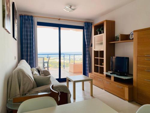 een woonkamer met een bank en een televisie bij SUNRISE ATALAYA Amanecer suite in Mojácar