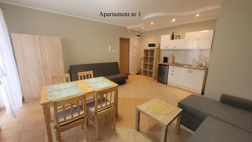a living room with a table and a kitchen at Apartament Rybacka 84m1 in Krynica Morska