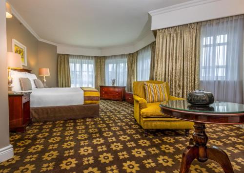 Hemingways Hotel في شرق لندن: غرفه فندقيه بسرير وكرسي وطاولة