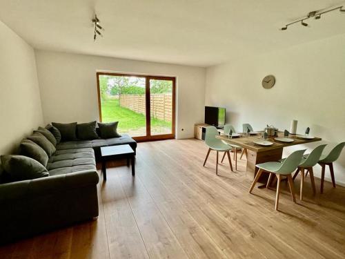 uma sala de estar com um sofá, uma mesa e cadeiras em Ferienwohnung am Wald 