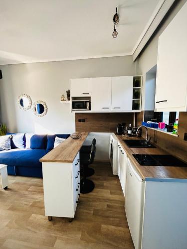 a kitchen with white cabinets and a blue couch at Urszula's apartment- apartment with pool in Kos in Psalidi