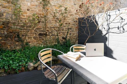 a table and chair with a laptop computer on it at Hôtel du Château Dinan - Originals Boutique in Dinan