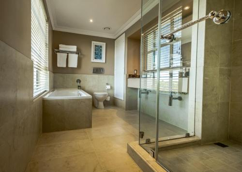 a bathroom with a shower and a tub and a toilet at Hemingways Hotel in East London