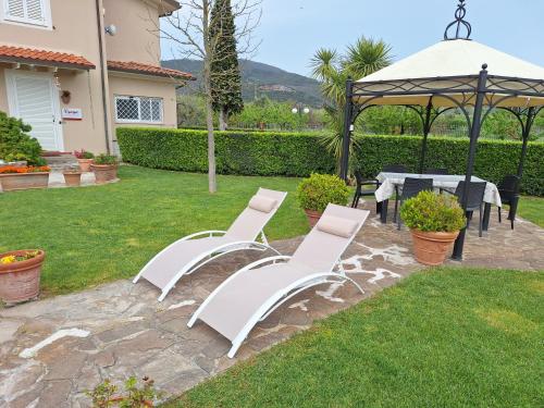 a group of white chairs and a table in a yard at leupupe relax cultura mare monti in Cascina