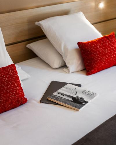 a book on a bed with two pillows and a keyboard at Hôtel du Château Dinan - Originals Boutique in Dinan
