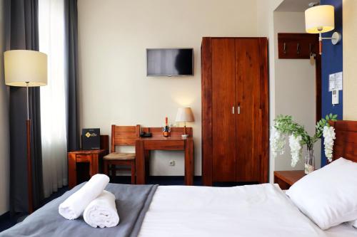 um quarto com uma cama e uma secretária com uma televisão em Hotel Piast Wrocław Centrum em Breslávia
