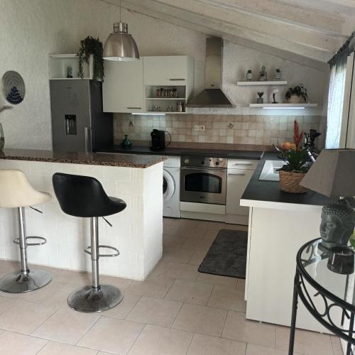 une cuisine avec des armoires blanches et un comptoir noir dans l'établissement Maison bord de mer, à Penta-di-Casinca