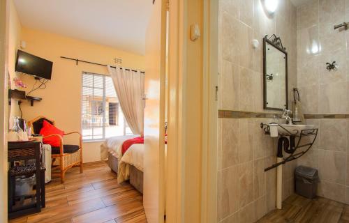 uma casa de banho com uma cama e um lavatório num quarto em All over Africa Guest house em Kempton Park