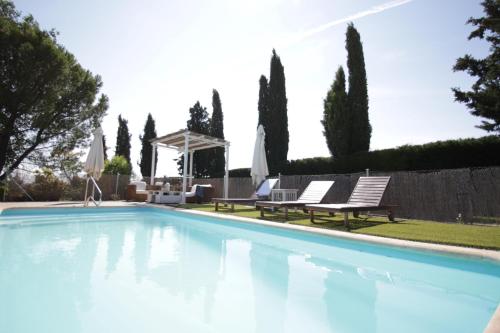 a swimming pool with two chairs and umbrellas at Casa de campo Villares in Dosbarrios