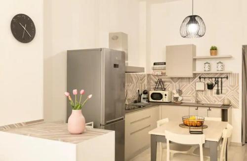 a kitchen with a refrigerator and a table with a vase of flowers at Pozzallo cozy house vista mare in Pozzallo