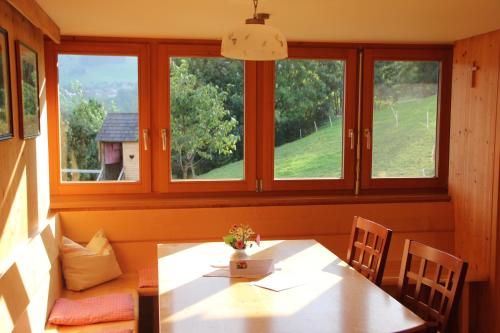a dining room with a table and two windows at Bio Ferienbauernhof Greber in Schwarzenberg im Bregenzerwald
