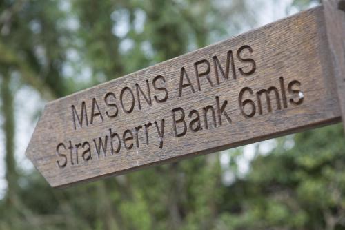 una señal de madera con las palabras "brazos masónicos" bandas de bancos de fresas en The Wheatsheaf Inn, en Kendal