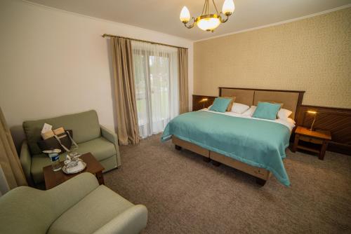 um quarto de hotel com uma cama e um sofá em Oravský Háj Garden Hotel & Resort em Trstená