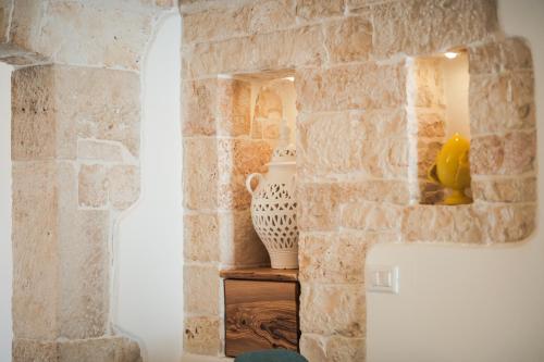 a room with a stone wall and a table with a vase at San Matteo Dimore di Charme in Putignano