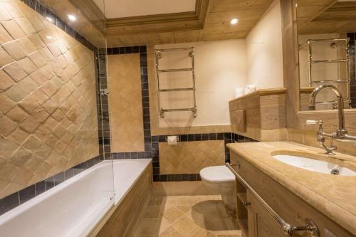 La salle de bains est pourvue d'une baignoire, de toilettes et d'un lavabo. dans l'établissement Val d’Isère - Extraordinaire Chalet Montana avec piscine sur la piste Olympique de Belevarde., à Val dʼIsère