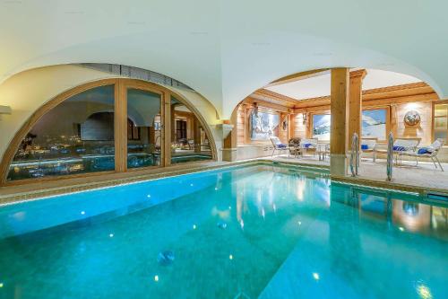 uma grande piscina numa casa com tecto arqueado em Val d’Isère - Extraordinaire Chalet Montana avec piscine sur la piste Olympique de Belevarde. em Val dʼIsère