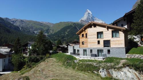 a house on a hill with a mountain in the background at Chalet Coral und Zermatter Stadel in Zermatt