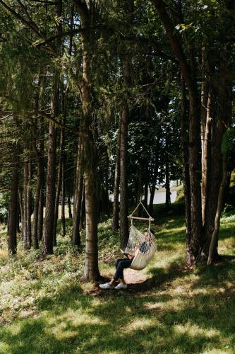 a person sitting on a hammock in a park at Poziom 511 Jura Wellness Hotel & Spa in Ogrodzieniec