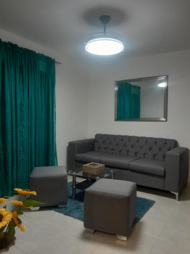 ein Wohnzimmer mit einem Sofa und grünen Vorhängen in der Unterkunft Res Quintas Palmeras IV in Santiago de los Caballeros