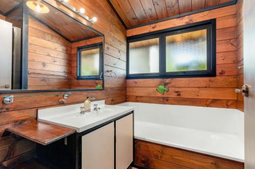 La salle de bains est pourvue d'un lavabo et d'une baignoire. dans l'établissement Pauanui Beach House Suntrap, à Pauanui