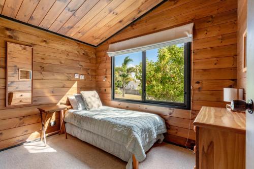 a bedroom with a bed and a window at Pauanui Beach House Suntrap in Pauanui