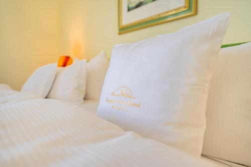 a white bed with a pillow with a sign on it at Rugard Thermal Strandhotel in Binz