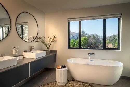 a bathroom with two sinks and a tub and mirrors at Cradle Boutique Hotel in Lanseria