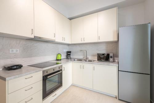 a white kitchen with white cabinets and a refrigerator at Kastela's Harbor Retreat with Jacuzzi in Piraeus