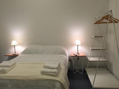 a bedroom with a bed with two lamps and two shelves at Ukurj Apartamentos in Ushuaia