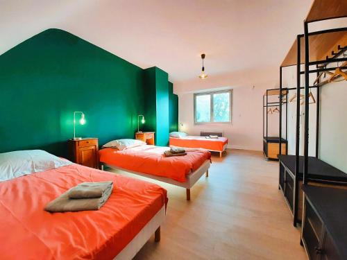- une chambre avec 2 lits et un mur vert dans l'établissement La Belle du bois, à Grimbosq