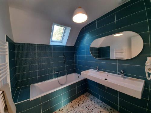 une salle de bain avec une baignoire, un lavabo et un miroir dans l'établissement La Belle du bois, à Grimbosq