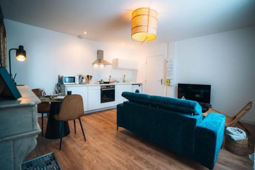 a living room with a blue couch and a kitchen at Le Blue Berry • Élégant & Fonctionnel • Proche Gare in Châteauroux