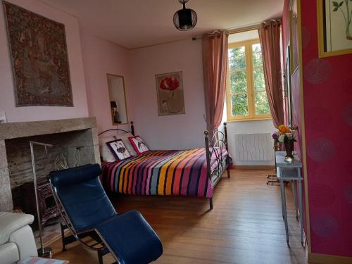 a bedroom with a bed and a chair and a fireplace at Le Petit Manoir in Isigny-le-Buat