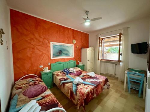 a bedroom with two beds and an orange wall at Poesia del Salento in Roca Vecchia