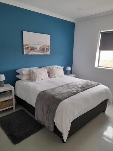 a bedroom with a large bed with a blue wall at C-Rock Holiday Home Jacobs Bay in Jacobs Bay