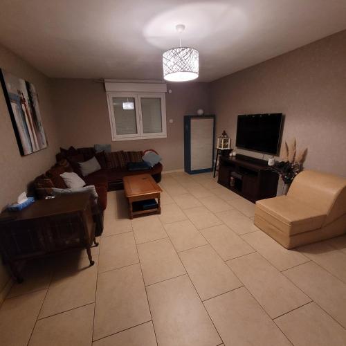 un salon avec des canapés et une télévision à écran plat dans l'établissement Charmante maison équipée pour un séjour agréable, à Valmont