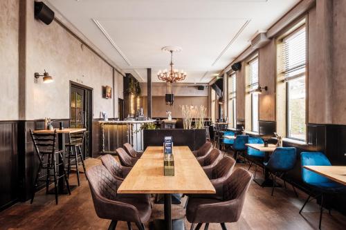 ウェーメルディンゲにあるHotel Brasserie Smitsの木製のテーブルと椅子と窓のあるレストラン