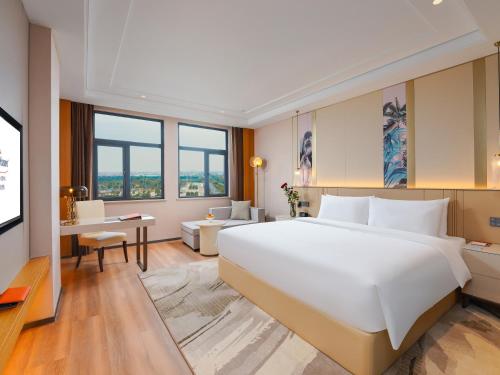 sypialnia z dużym białym łóżkiem i biurkiem w obiekcie Howard Johnson by Wyndham Huaqiao Plaza Xinyu w mieście Xinyu