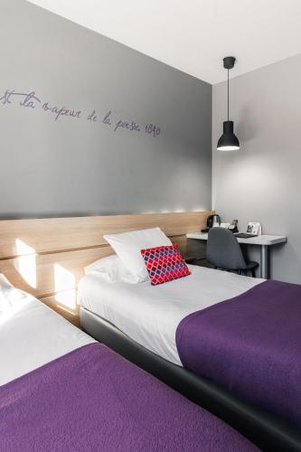 a hotel room with two beds and a desk with a chair at Hôtel du Château Dinan - Originals Boutique in Dinan