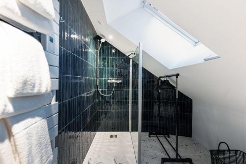 a bathroom with a shower with black tiles at Hôtel du Château Dinan - Originals Boutique in Dinan