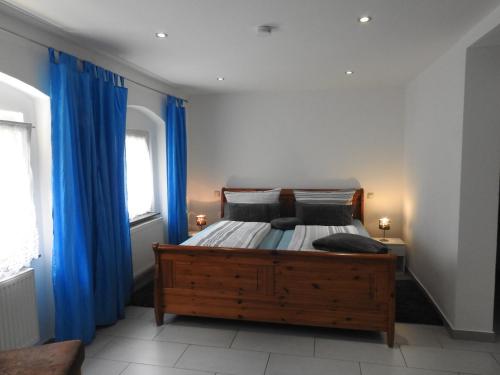 a bedroom with a wooden bed with blue curtains at Ferienwohnungen am Hauptplatz in Pirna